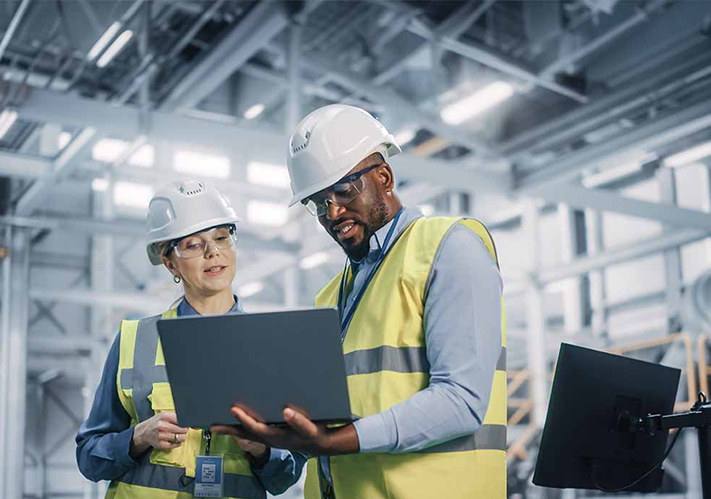 A group of individuals wearing hard hats and reflective yellow jackets, engaged in a work environment.
