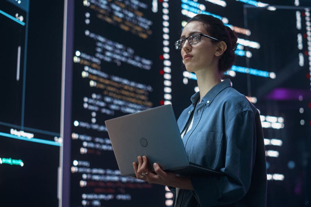 Portrait of Woman Creating a Software and Coding, Surrounded by Big Screens Displaying Lines of Programming Language Code. Female Programmer Working in a Monitoring Room. Futuristic Concept